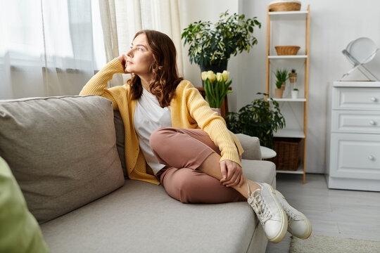 Middle aged woman sitting on a cozy couch in a stylish living room.