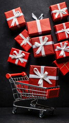 Fototapeta premium red gift boxes on shopping cart on black background with copyspace