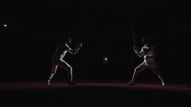 Rivals In Fencing Track, Full-Length Slow Motion Shot With Two Male Fencers In Darkness, Epic Duel