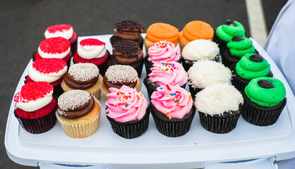 Assorted flavored cupcakes displayed on a white tray
