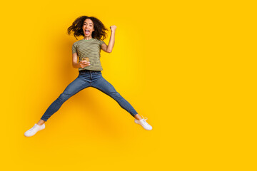 Full size photo of overjoyed funky girl dressed t-shirt hold smartphone jumping win lottery yell...