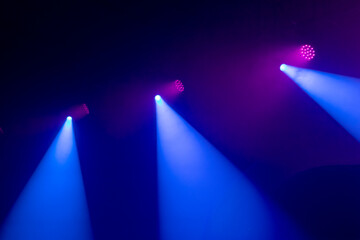 An empty stage, lit by spotlights and smoke before the performance