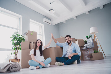 Full size photo of two young partners sitting floor high five relocating moving box package new...