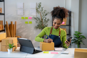 A woman is sitting at a desk with a laptop and a cell phone