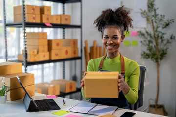 A woman is smiling and holding a cardboard box