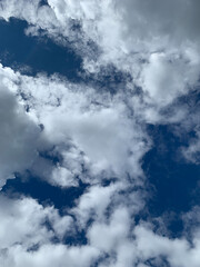 A clear blue sky with fluffy white clouds in various formations, captured on a bright day
