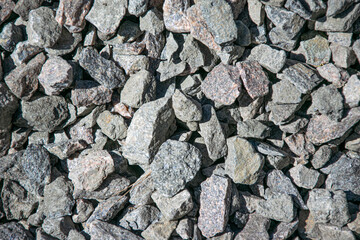 A close-up shot of a pile of grey and pink gravel rocks. The rocks are various sizes and shapes,...