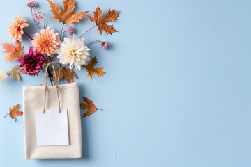 Autumn leaves and flowers with shopping bag on blue background concept for fall season or gift ideas.