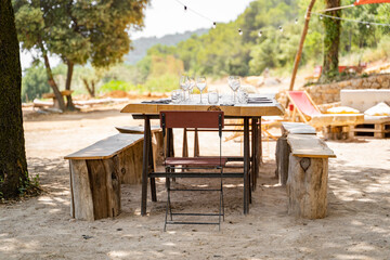 A beautifully set rustic outdoor dining table in a scenic countryside setting, perfect for gatherings or celebrations.