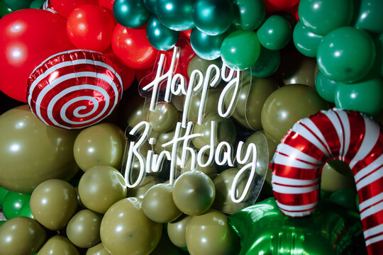 A neon sign with a green and red striped cactus and a green and red striped candy cane with the words Happy Birthday written on it - Powered by Adobe