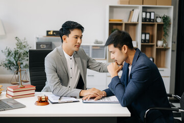 Business people compassionately holding hands and discussing contract papers with laptop and tablet at office room...