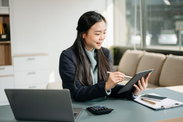 Business woman using tablet and laptop for doing math finance on an office desk, tax