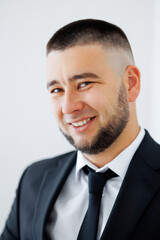 A man with a shaved head and a beard is smiling and wearing a suit and tie. He looks confident and professional