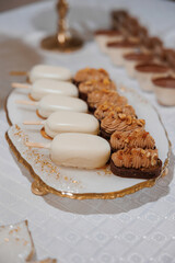 A white plate with a variety of desserts including a white cake and brownies. The desserts are arranged in a visually appealing manner, with the white cake in the center