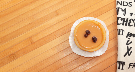 A delicious circular dulce de leche dessert with a cloth napkin on a wooden table with copy space. Traditional Colombian sweet product.