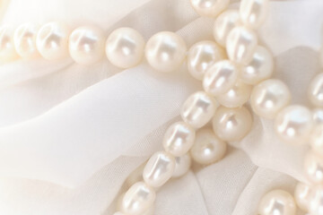 A string of pearls gracefully rests on a white backdrop, blurring softly at the edges. The image is a quaint juxtaposition to the sharp, high-definition visuals trending in today's digital landscape.