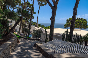 A tranquil luxury resort with white buildings, lush greenery, and a scenic sea view in Capri Island, Italy.