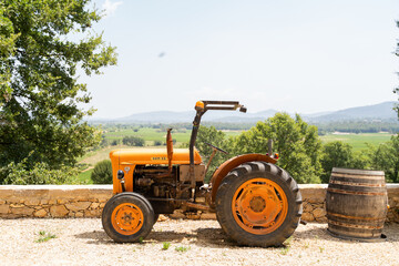 A classic orange tractor and barrel set against a picturesque countryside, great for agricultural imagery and themes