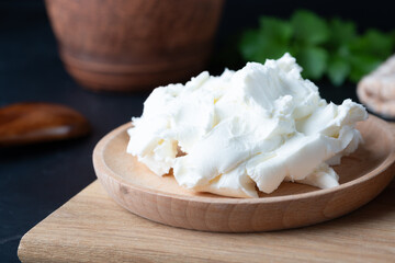 Cream cheese in a wooden bowl on a dark wooden background