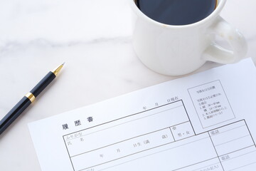 コーヒーを飲みながら、履歴書を書く
