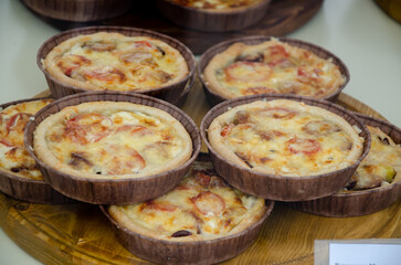 Delicious and fresh desserts in the form of tartlets on display behind glass