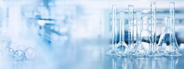 glass flask and cylinder in chemistry science lab blue banner background