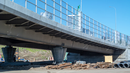 Obraz premium Construction of bridges and roads. A noise-proof coating has been installed on the bridge under construction. The bridge supports are made of reinforced concrete. A construction site.