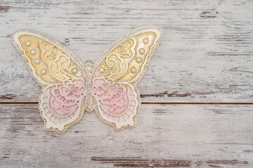 Decorative butterfly with ornaments and intricate design in pastel colors, displayed on a white wooden surface, with copy scape.