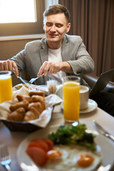 Pleased businessman having breakfast in his suite