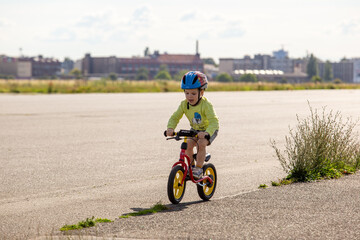 Obraz premium Kleinkind spielt mit dem Fahrrad auf dem Tempelhofer Feld, Berlin