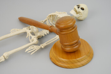 Skeleton and judge gavel on grey. Homicide legal trial concept.