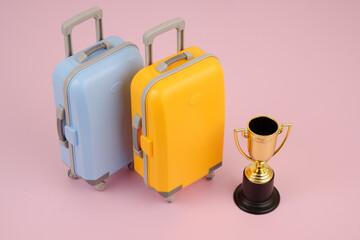 Travel to visit sport events concept. Gold champion cup and travel suitcases on pink background.	