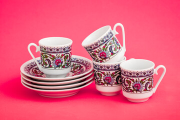 Elegant porcelain Turkish coffee cups with decorative pattern on pink background.