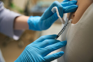 Dermatologist anesthetizing patient affected skin area before new growth removal