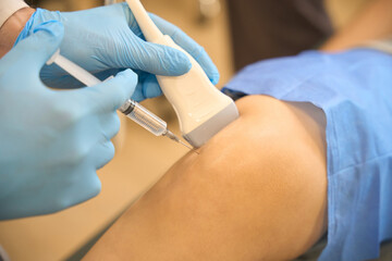 Surgeon performing ultrasound-guided lower extremity joint aspiration