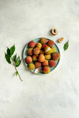 Juicy lychee fruit with cut in half and green leaves, top view. Fresh ripe tropical fruit