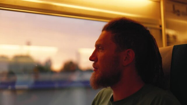 Man travelling by train looks out of window
