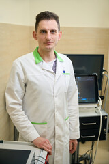 Fototapeta premium Diagnostician posing for camera with ultrasonic medical equipment in background