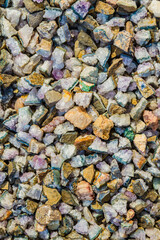 Close view of a collection of various polished stones and pebbles in different shapes, sizes, and colors, including shades of green, beige, and brown.