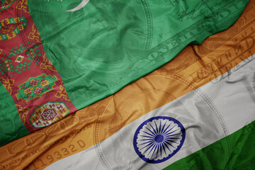 waving colorful flag of india and national flag of turkmenistan on the dollar money background....