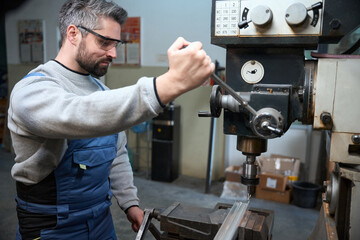 Bearded worker at his workplace at a modern machine