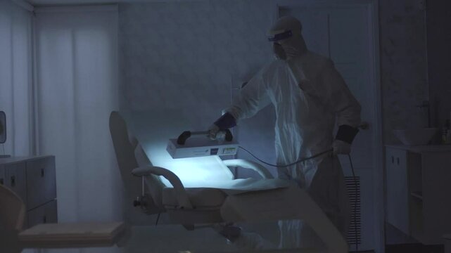 personal de sanidad desinfectando una silla de cirugia con luz ultravioleta en un hospital