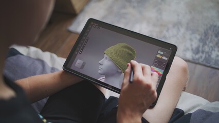 Boy with digital stylus and tablet in hands sits at home, creates 3d models. Focused teenager draws clothes for game character using 3d modeling program. Development and game design concept. Close up.