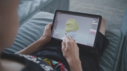Boy with digital stylus and tablet in hands sits at home, creates 3d models. Focused teenager draws clothes for game character using 3d modeling program. Development and game design concept. Close up.