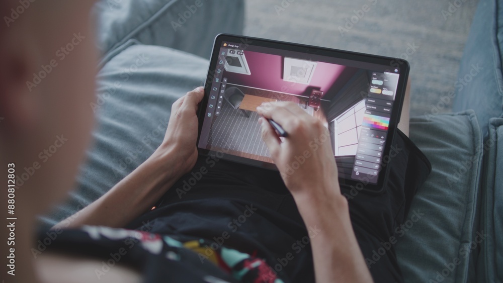 Poster talented teenager with digital stylus and tablet in hands sits at home, creates 3d model of room. cr