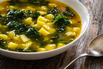 Portuguese green soup - Caldo Verde.  Potato and kale soup served in white bowl on wooden table