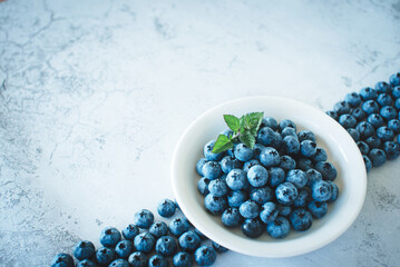 Ripe blueberries in a white plate and a pattern of berries on a white background. Healthy food dessert. Summer diet.