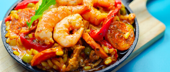 A black pan filled with a variety of food including shrimp, peppers, and corn