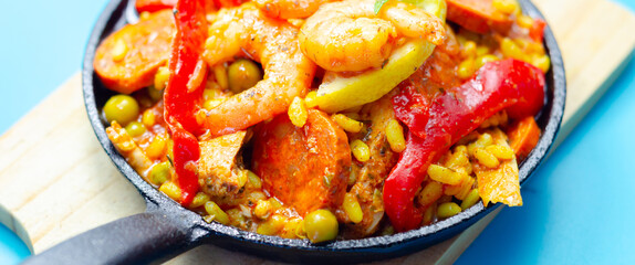A black pan filled with a variety of food including shrimp, peppers, and corn