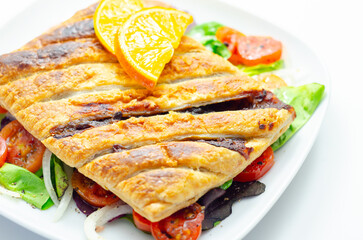 A plate of food with a pastry and a slice of orange on top